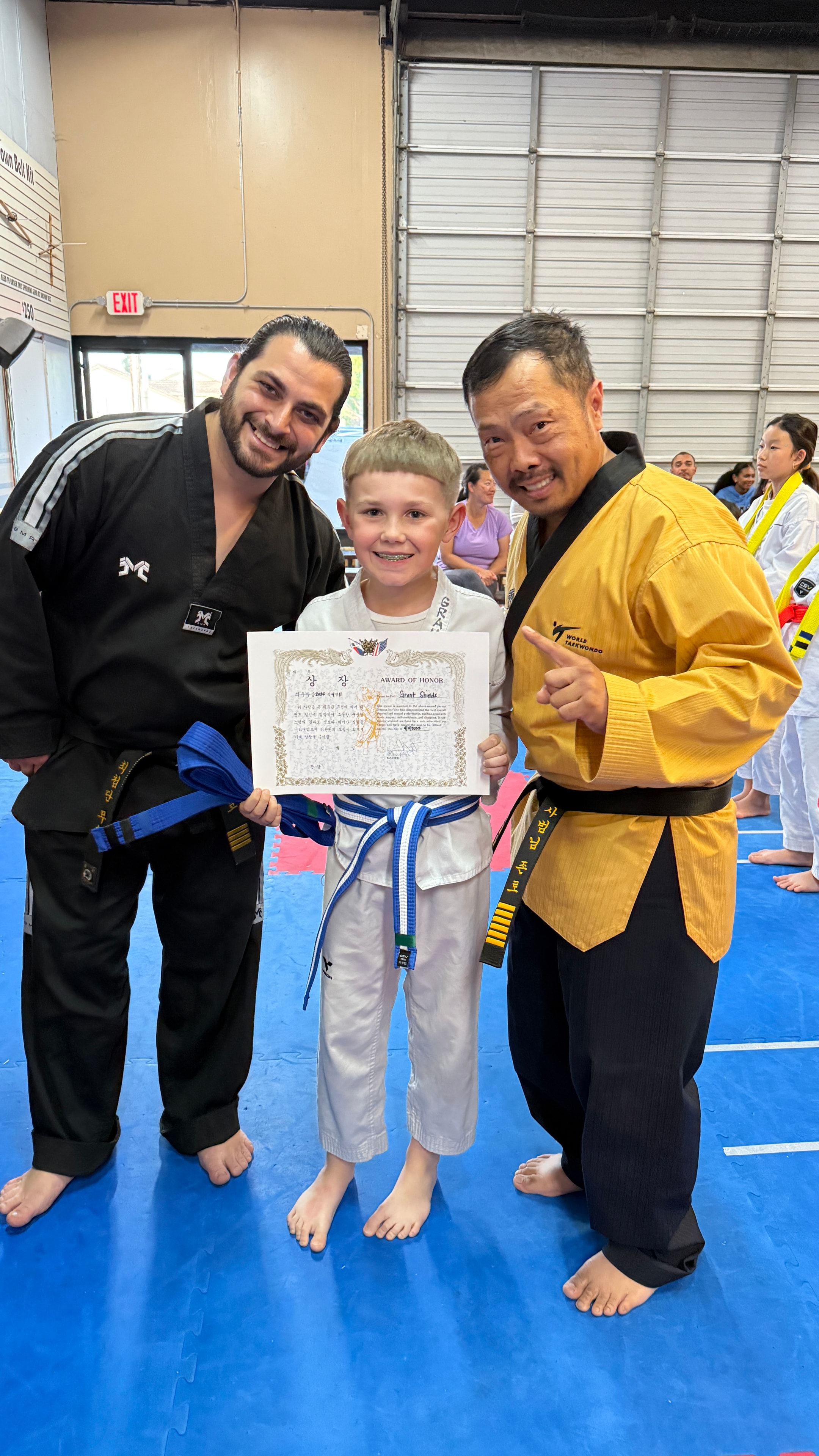 Young martial artist receiving an award with instructors
