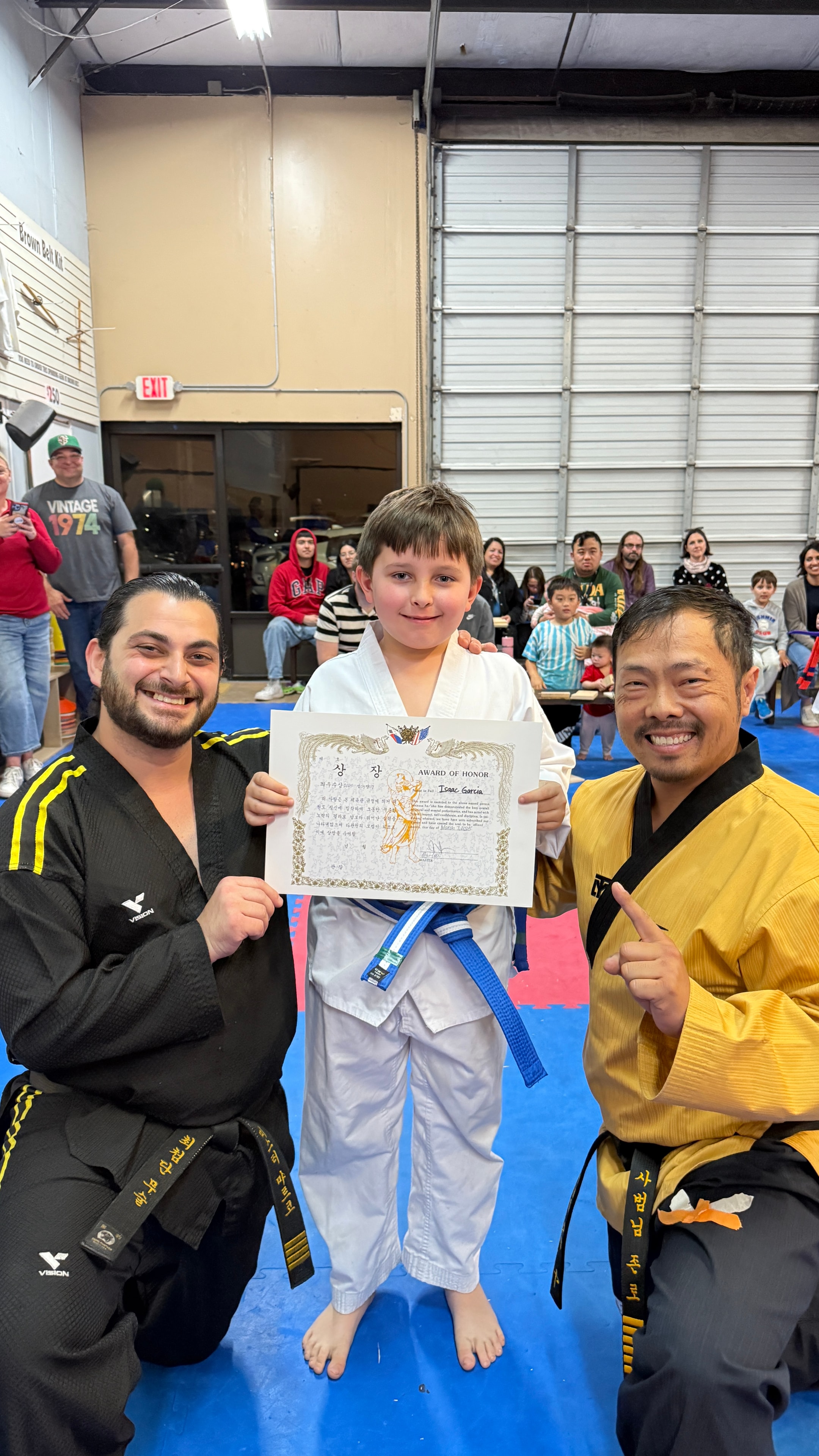 Young martial artist holding a certificate with instructors