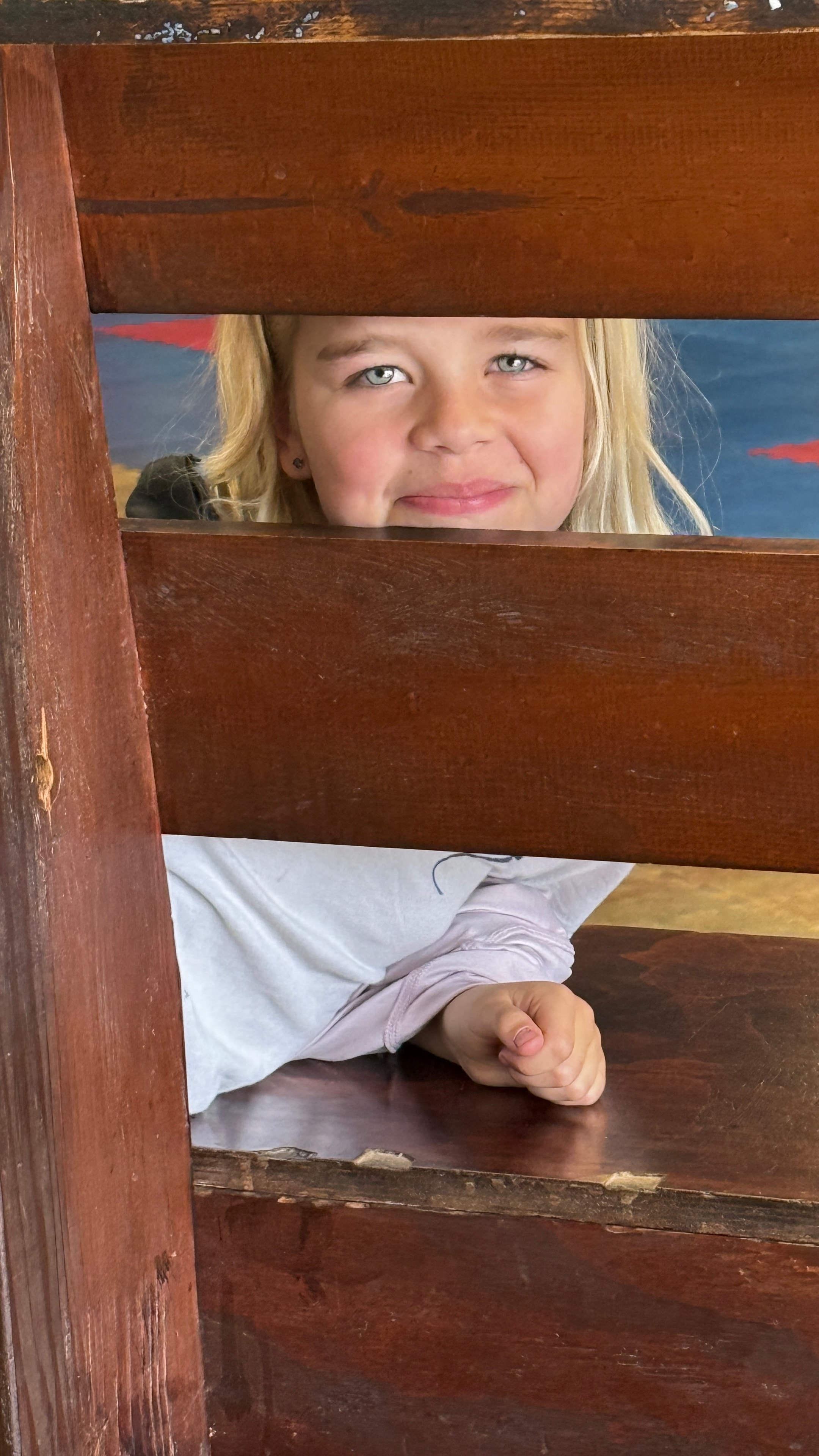 Young child peeking through wooden slats at the studio