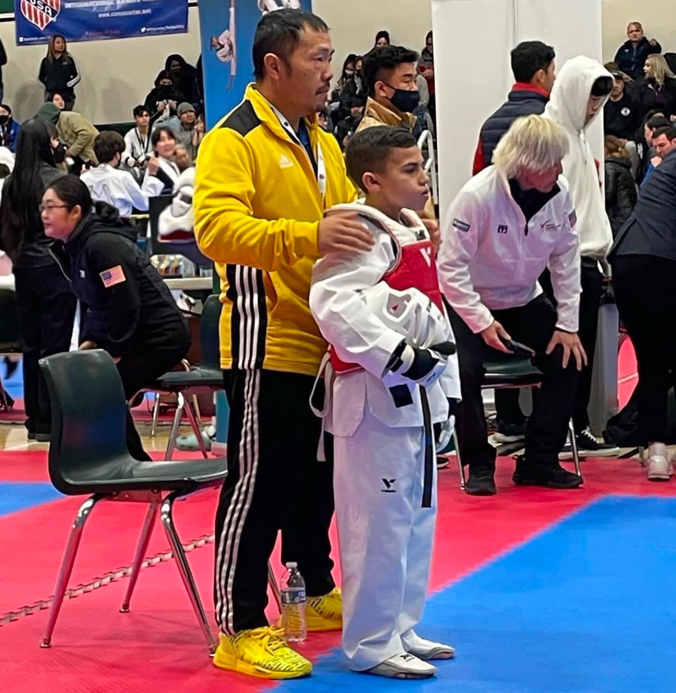 Coach supporting a young martial arts athlete at a competition