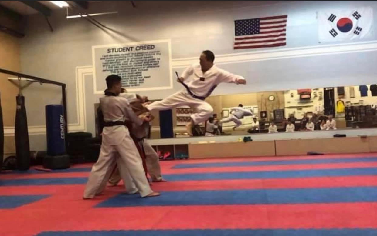 Martial artist performing a flying kick in the dojo