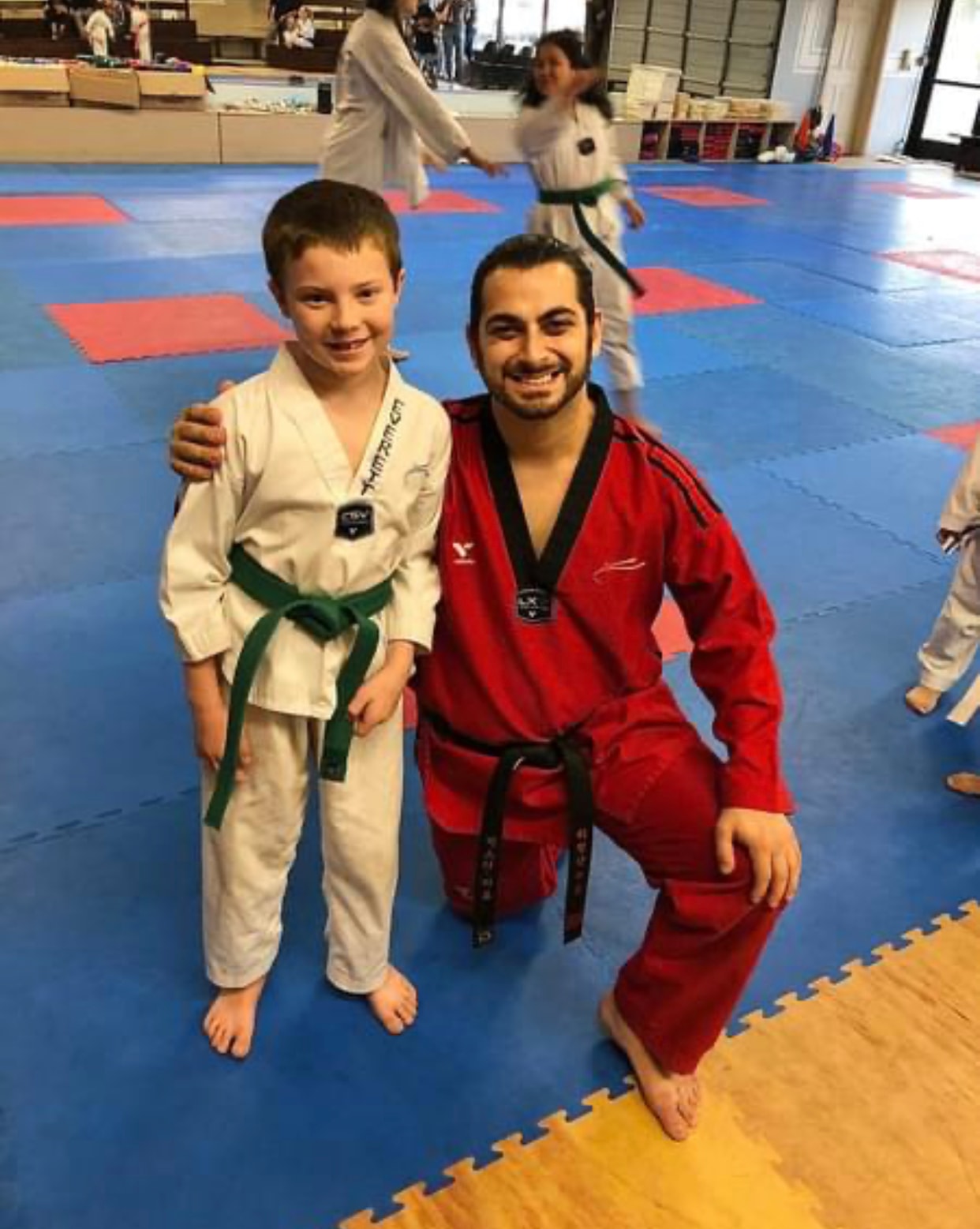 Martial arts instructor posing with a green belt student