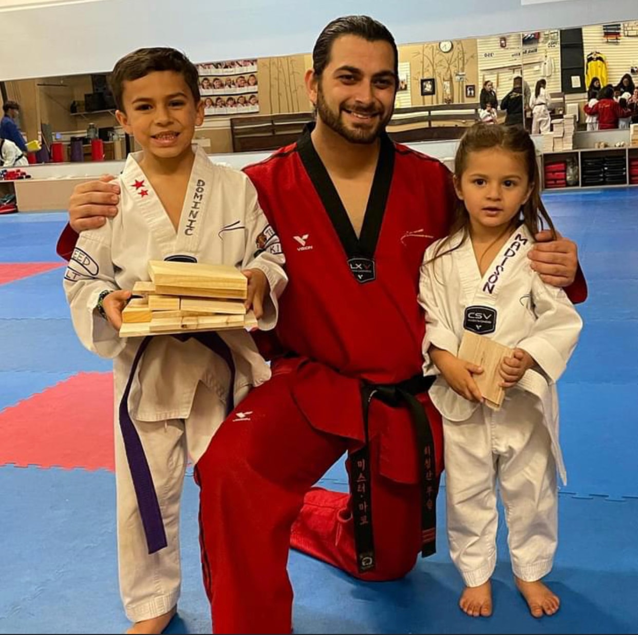 Martial arts instructor with two students holding breaking boards
