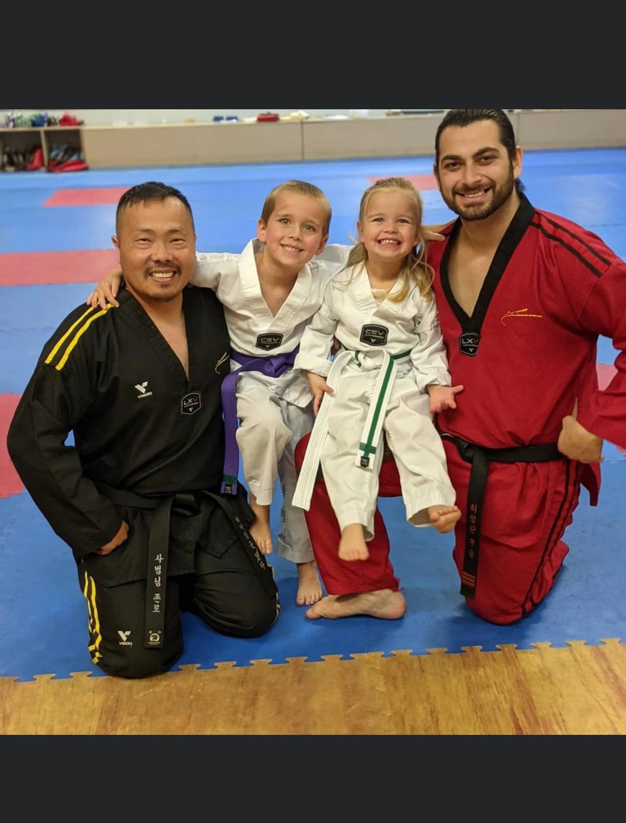 Two martial arts instructors posing with young students