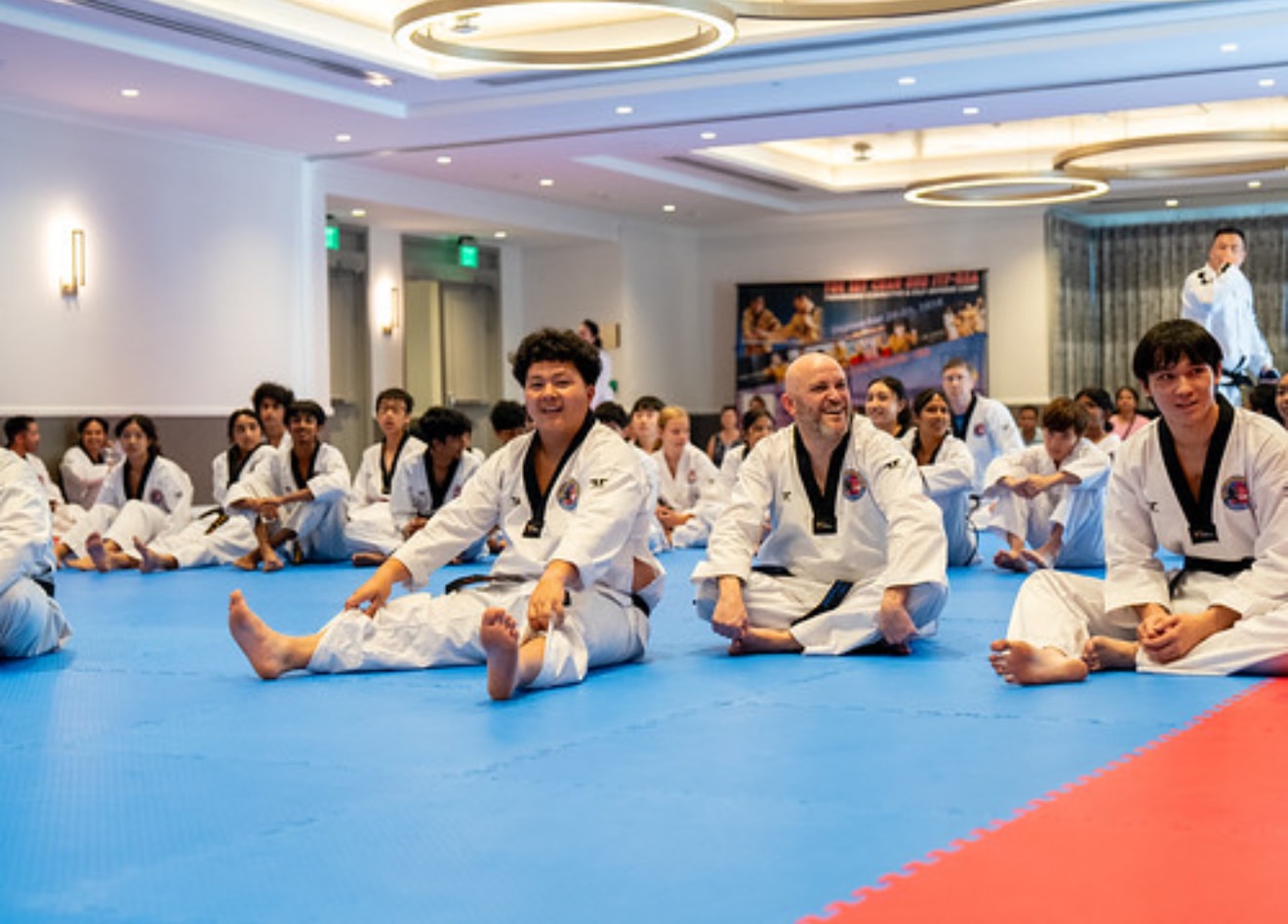 Martial arts students seated together on training mats