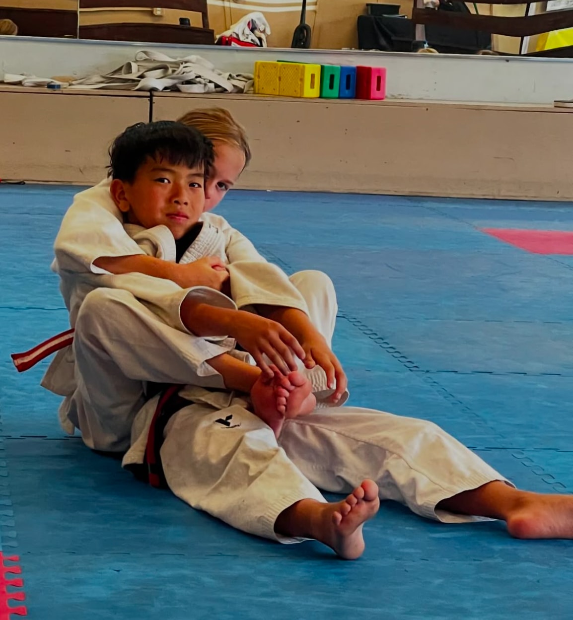 Two young martial arts students practicing on a mat